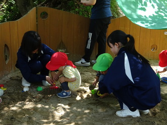 明星認定こども園　砂遊び子どもと一緒に笑顔で活動中