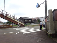 自転車通学生が、交通量の多い横断歩道を渡るため先生が見守っています。